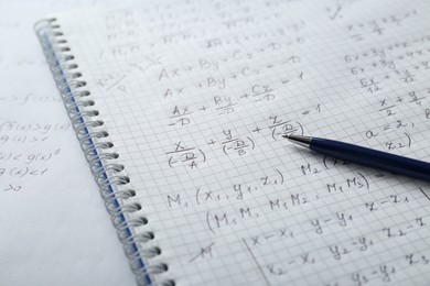Photo of Notebook with different mathematical formulas and pen, closeup