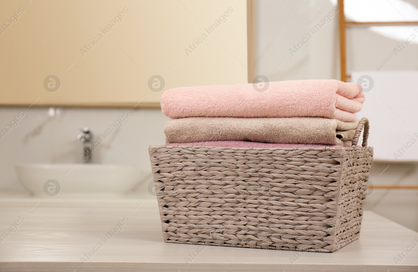 Photo of Laundry basket with fresh towels on counter in bathroom