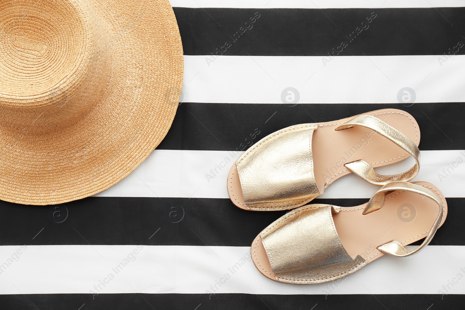 Photo of Stylish female shoes and straw hat on striped fabric