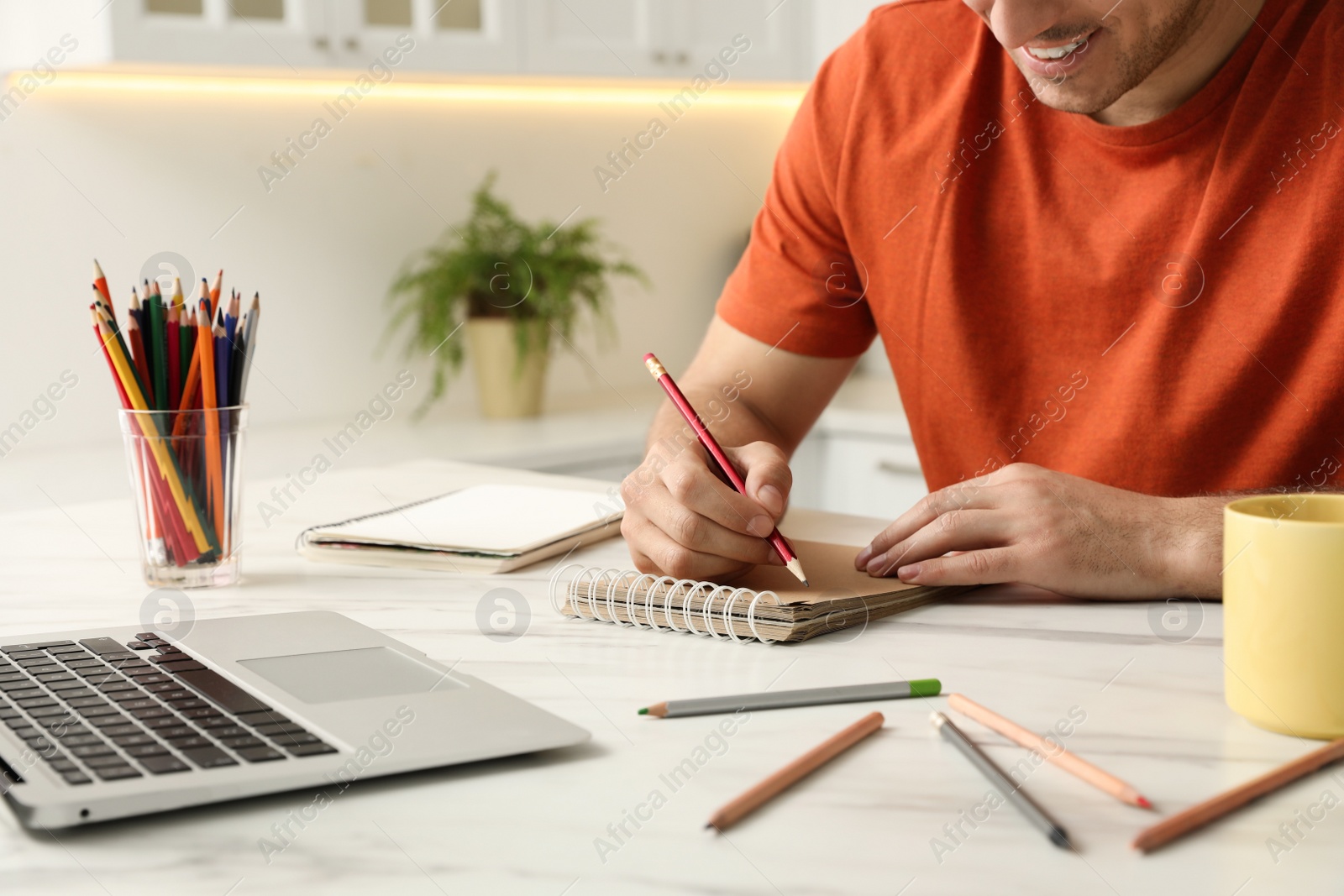 Photo of Man drawing in notebook at online lesson indoors, closeup. Distance learning