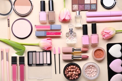 Flat lay composition with different makeup products and beautiful spring flowers on beige background