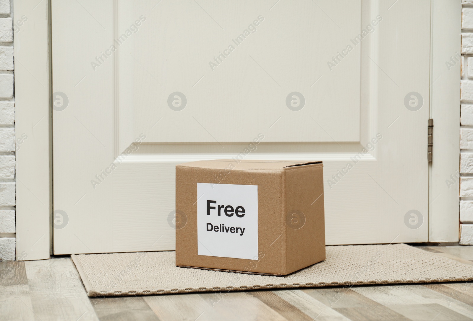 Photo of Parcel with sticker Free Delivery on rug indoors. Courier service