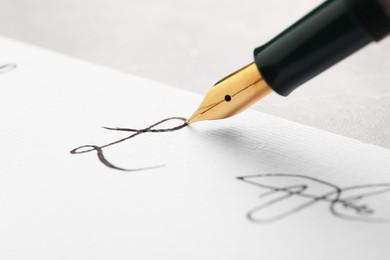 Photo of Signing on sheet of paper with fountain pen at table, closeup