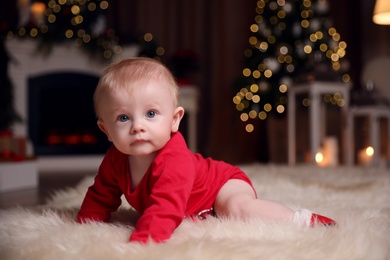 Photo of Cute little baby wearing red bodysuit on floor at home. Christmas celebration