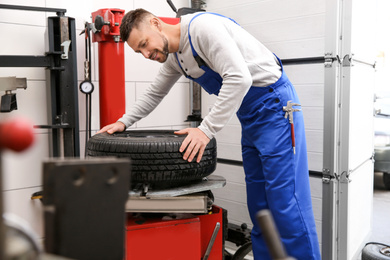 Mechanic working with tire fitting machine at car service