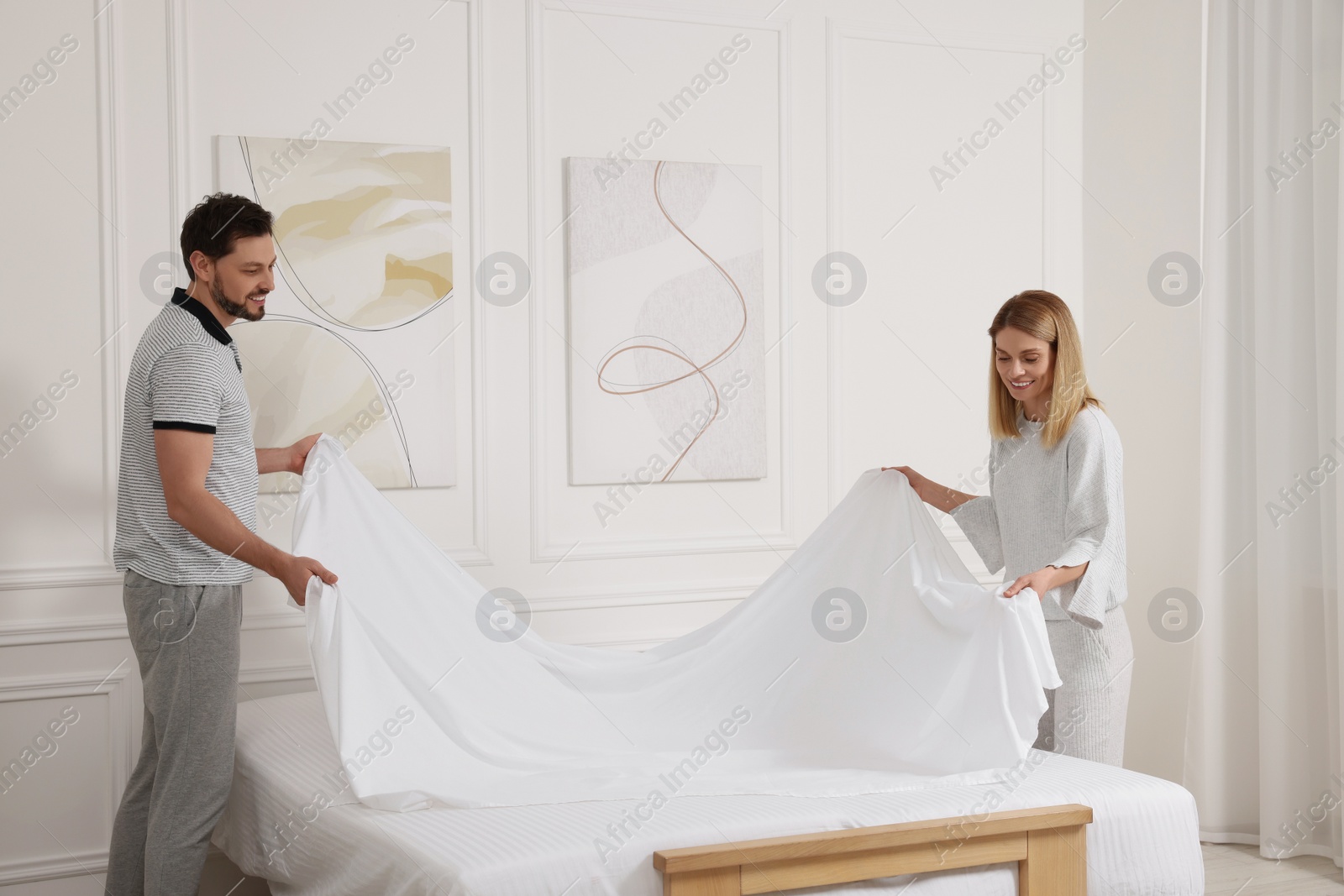 Photo of Couple changing bed linens at home. Domestic chores