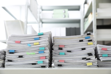 Stacks of documents with paper clips on office desk