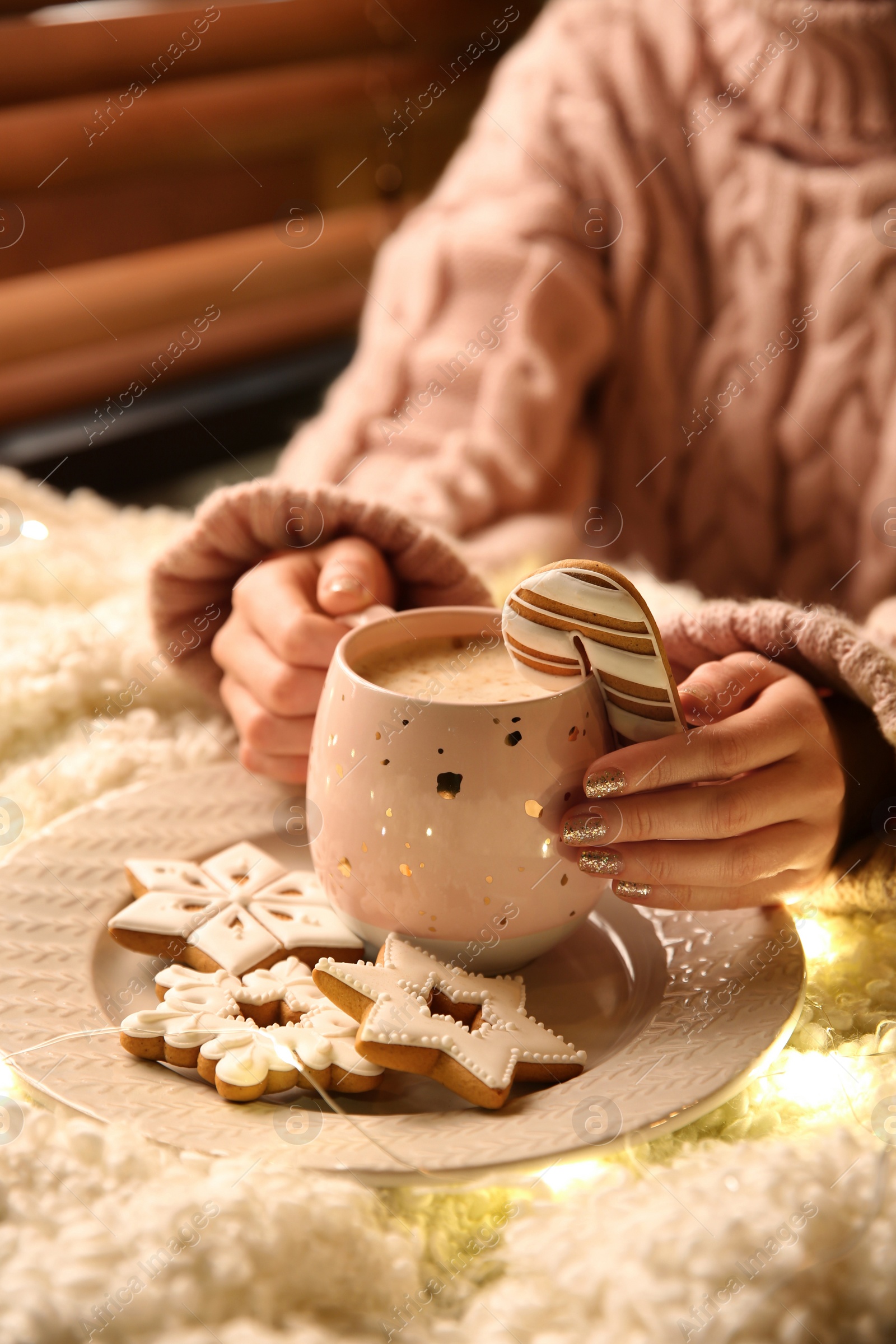 Photo of Woman with cup of hot drink and Christmas cookies at home, closeup