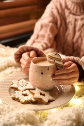 Photo of Woman with cuphot drink and Christmas cookies at home, closeup