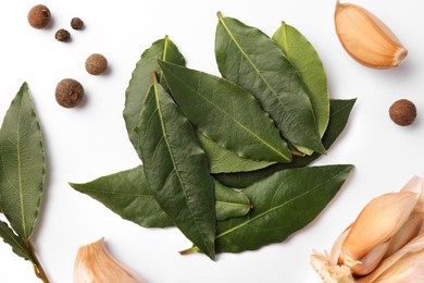 Photo of Aromatic bay leaves and spices on white background, flat lay