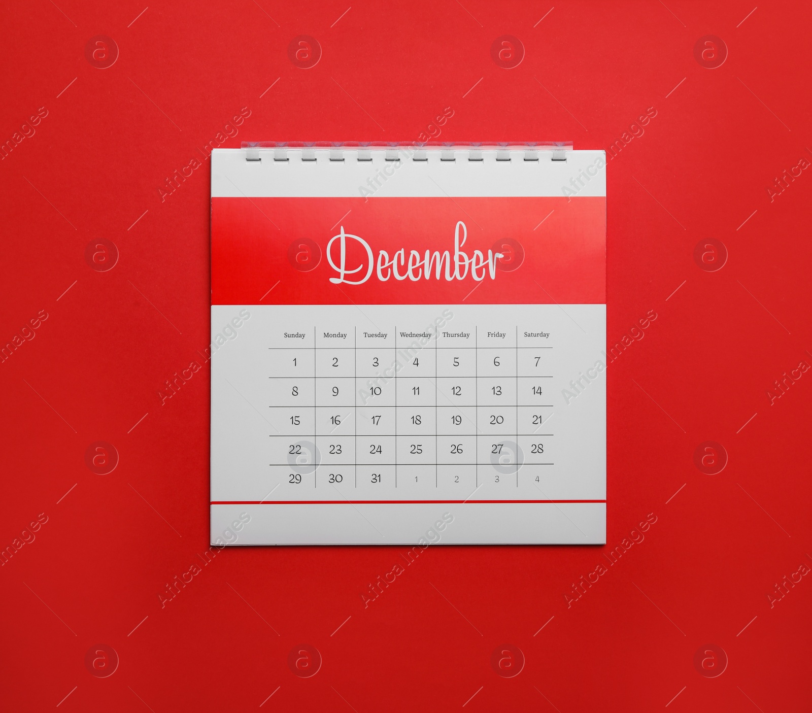 Photo of December calendar on red background, top view