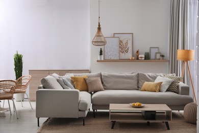 Photo of Stylish living room interior with comfortable grey sofa and coffee table