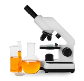 Laboratory glassware with orange liquid and microscope isolated on white