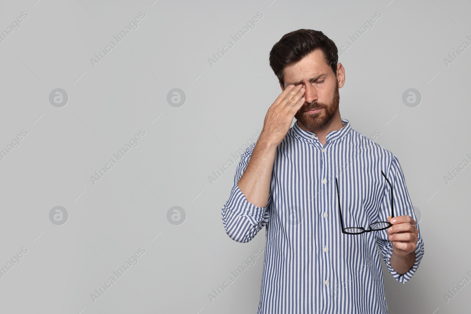 Photo of Man suffering from eyestrain on light grey background. Space for text