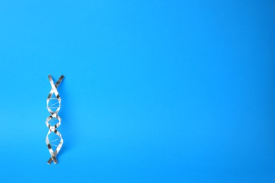 DNA molecular chain model made of metal on blue background, top view. Space for text