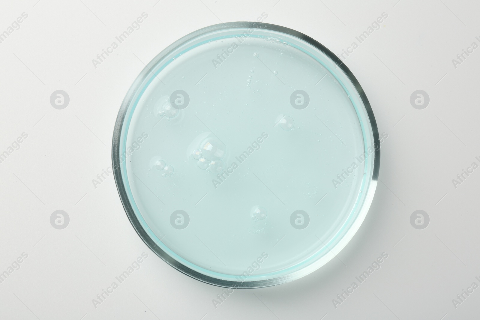 Photo of Petri dish with light blue liquid sample on white background, top view