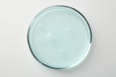 Petri dish with light blue liquid sample on white background, top view