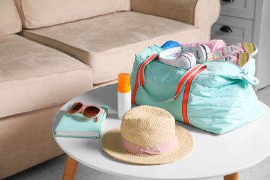 Photo of Bag and items for vacation on table in living room