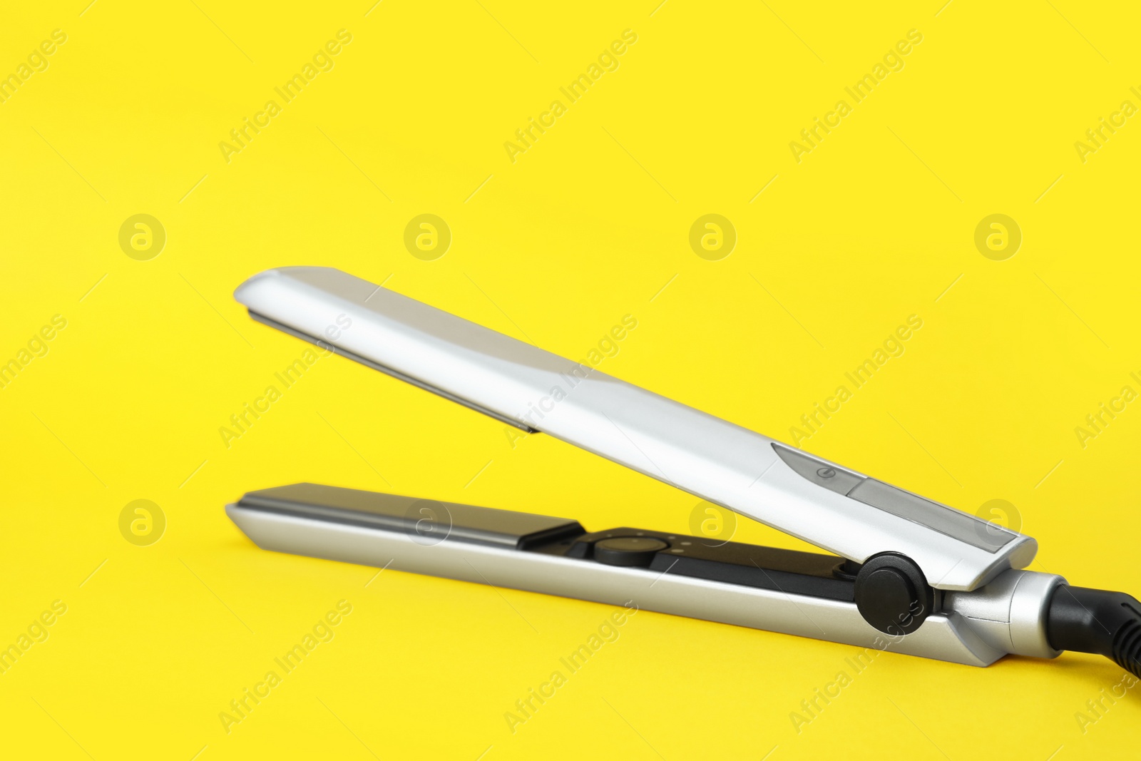 Photo of Modern hair iron for straightening on color background