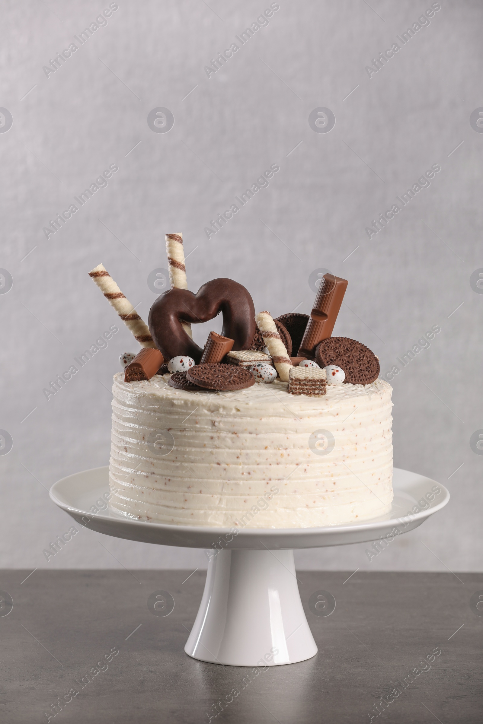 Photo of Delicious cake decorated with sweets on grey table