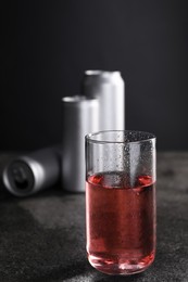 Photo of Energy drink in glass and aluminium cans on grey table