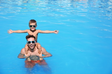 Photo of Little boy with father in swimming pool