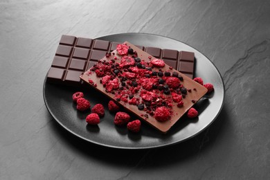 Photo of Plate and different chocolate bars with freeze dried fruits on slate table