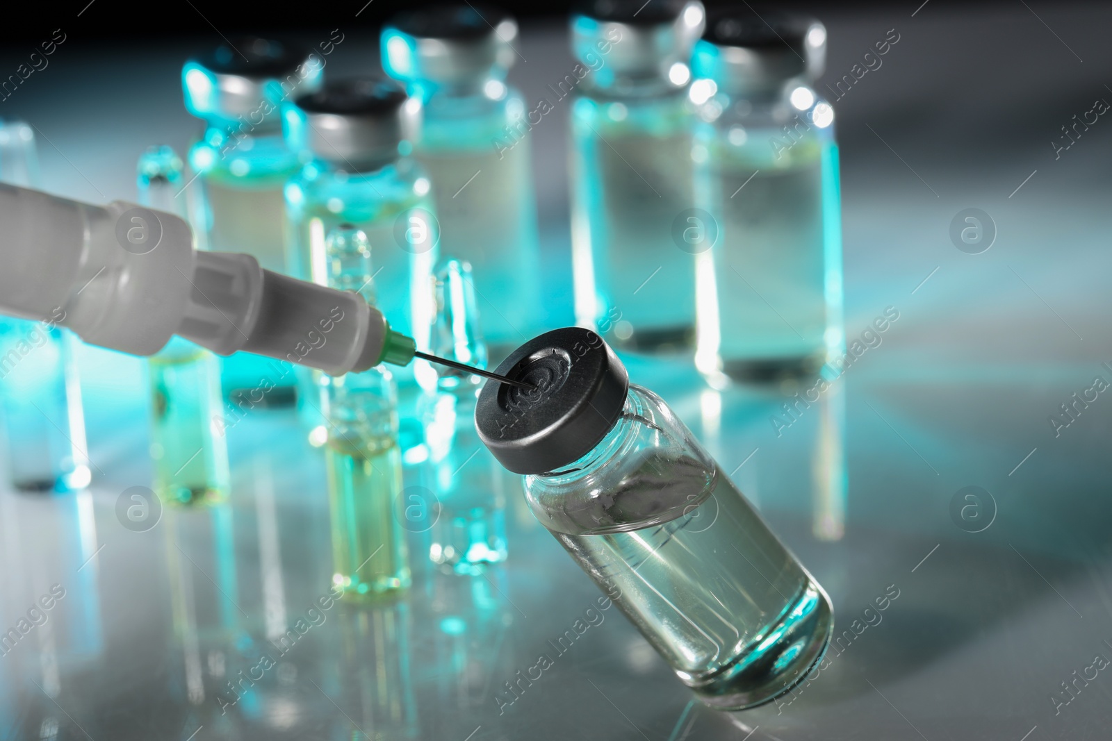 Photo of Filling syringe with medicine from vial on table, closeup