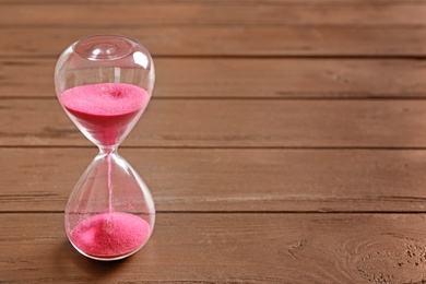 Photo of Hourglass with flowing sand on table. Time management