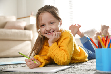 Photo of Little girl drawing on floor at home