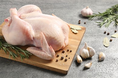 Photo of Fresh raw chicken with spices on grey textured table