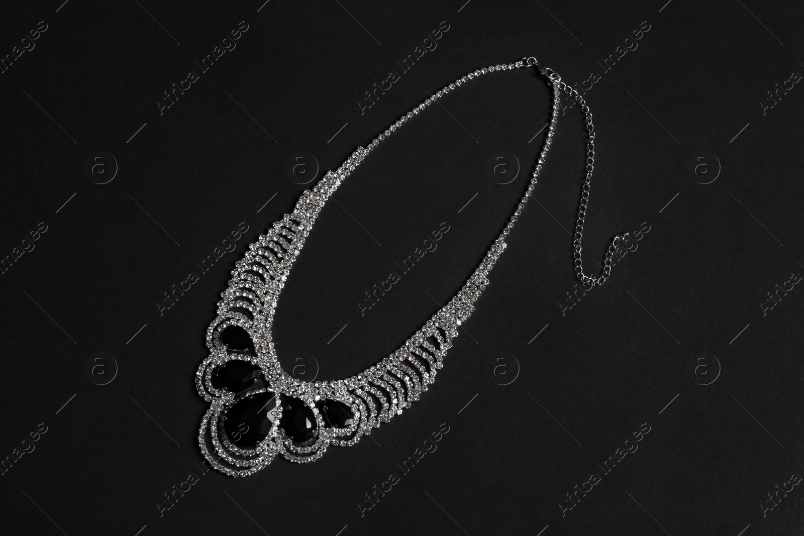 Photo of Stylish necklace with gemstones on black background, top view. Luxury jewelry