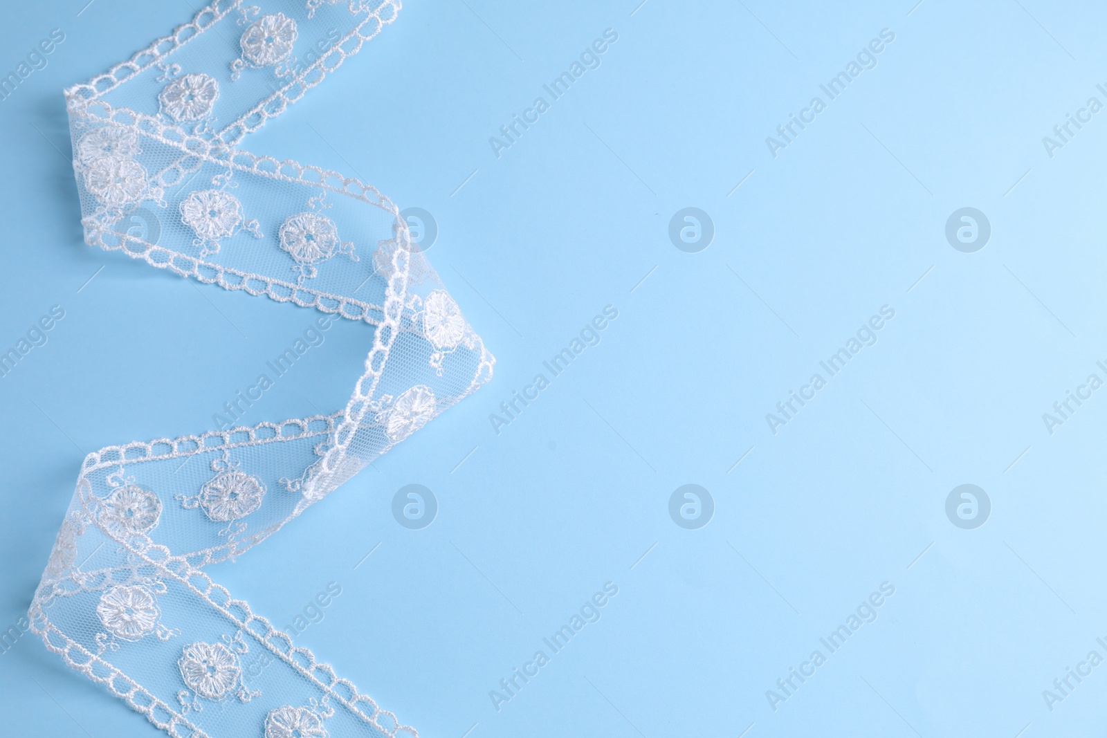 Photo of White lace on light blue background, top view. Space for text