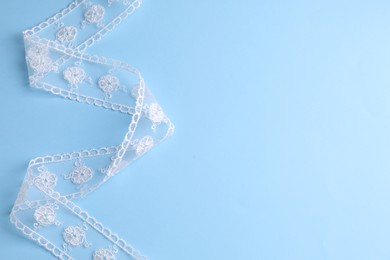 Photo of White lace on light blue background, top view. Space for text