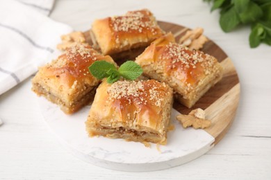 Photo of Eastern sweets. Pieces of tasty baklava on white wooden table, closeup