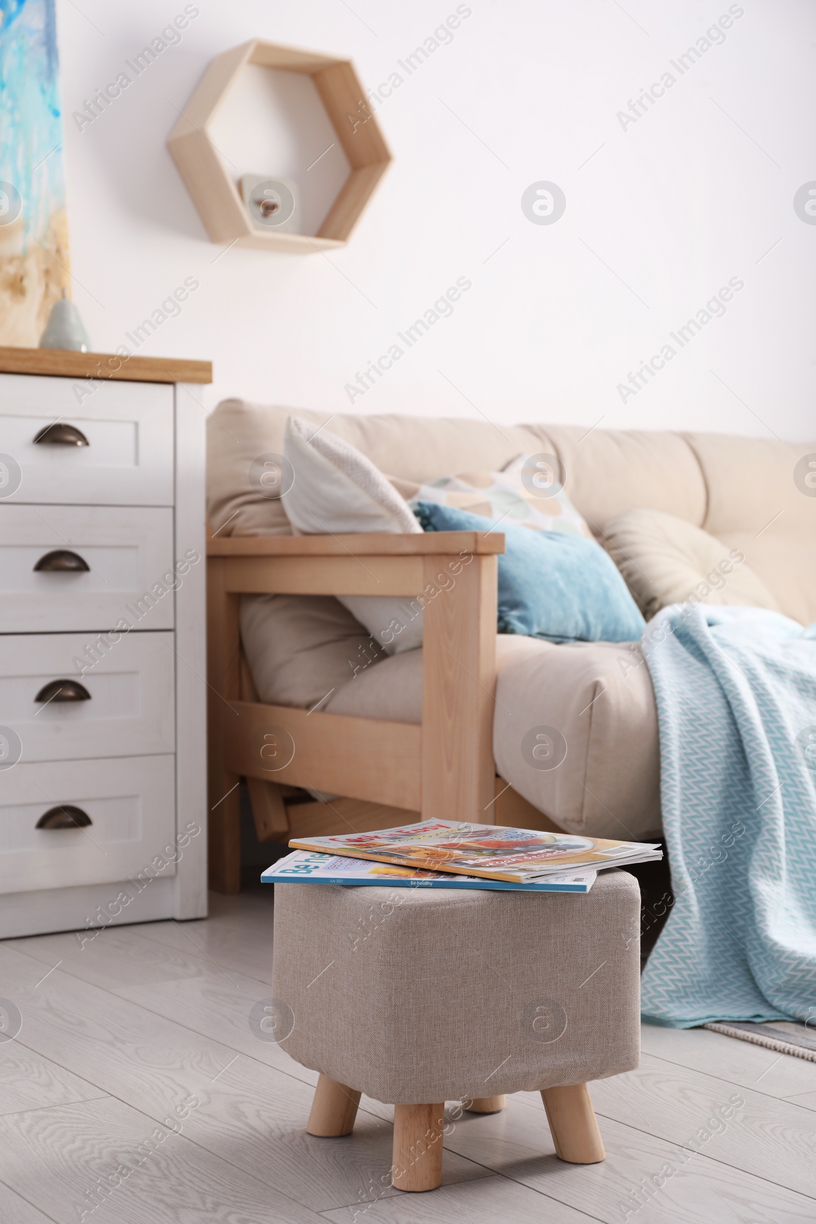 Photo of Stylish ottoman with magazines near sofa in light living room