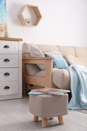 Stylish ottoman with magazines near sofa in light living room