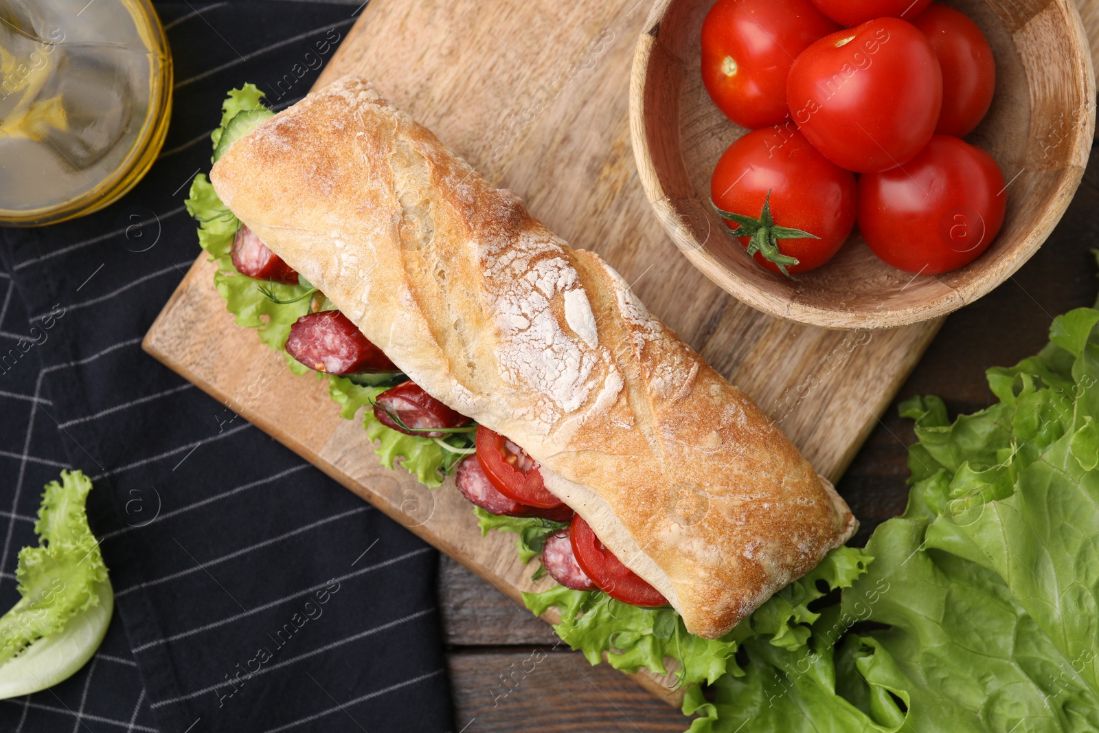 Photo of Delicious sandwich with sausages and vegetables on wooden table, flat lay