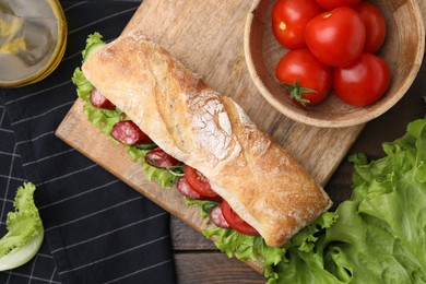 Photo of Delicious sandwich with sausages and vegetables on wooden table, flat lay