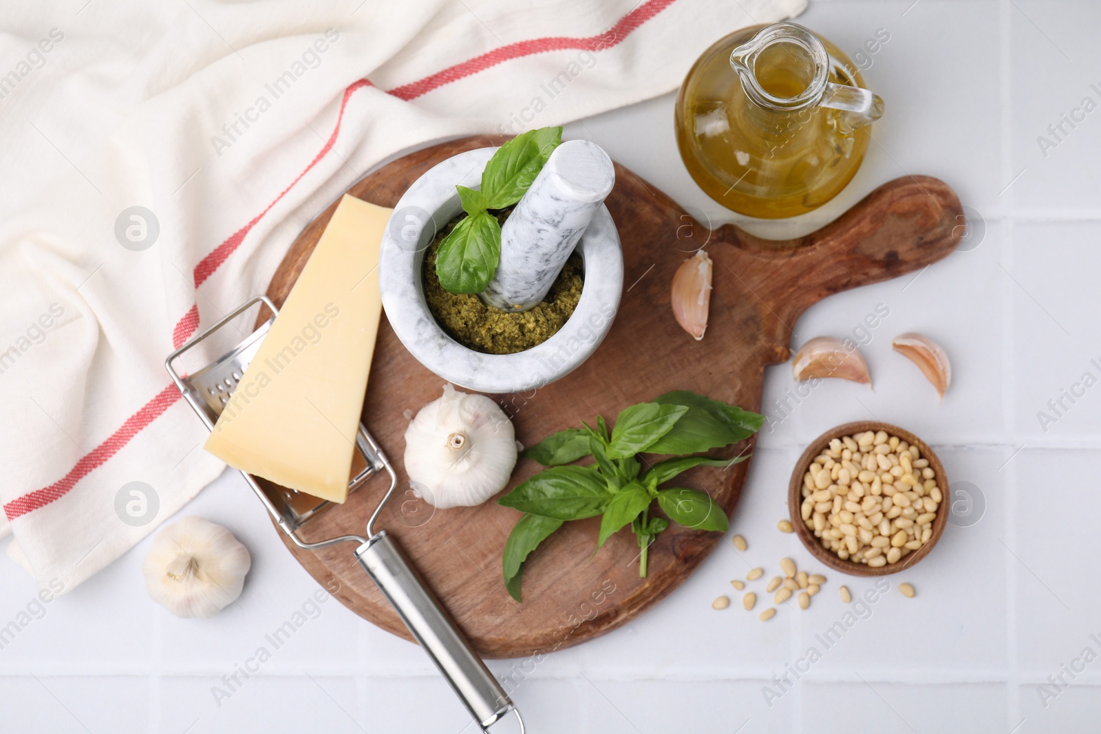 Photo of Different ingredients for cooking tasty pesto sauce on white tiled table, flat lay