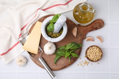 Photo of Different ingredients for cooking tasty pesto sauce on white tiled table, flat lay