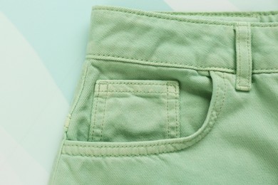 Photo of Stylish light green jeans on color background, closeup of inset pocket