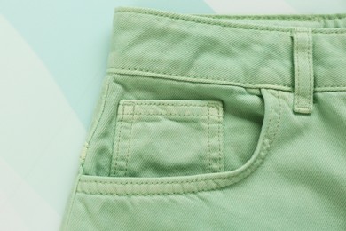 Stylish light green jeans on color background, closeup of inset pocket