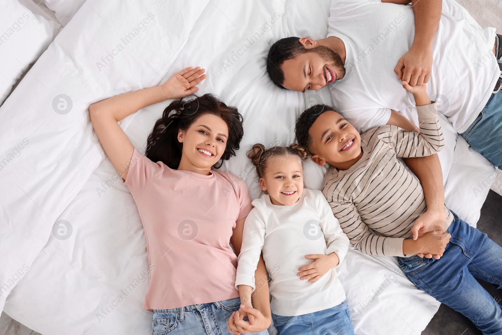 Photo of Happy international family lying on bed, top view