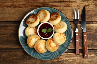 Photo of Delicious cottage cheese pancakes with jam and mint on wooden table, flat lay