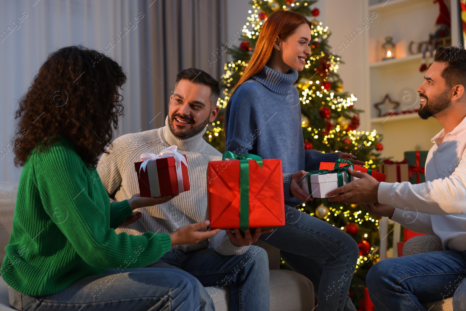 Photo of Christmas celebration. Happy friends exchanging gifts at home