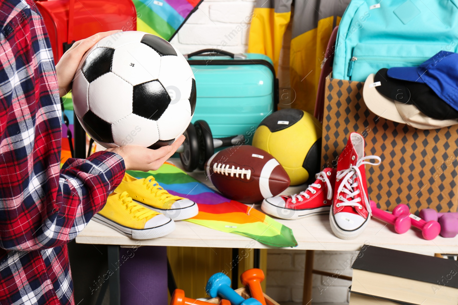 Photo of Woman holding ball near many different stuff indoors, closeup. Garage sale