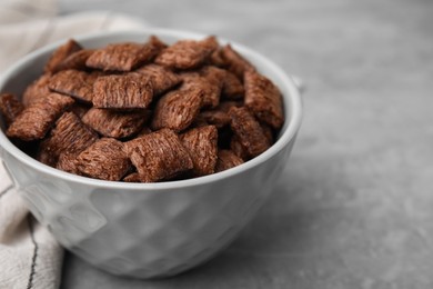 Photo of Chocolate cereal pads in bowl on grey table, closeup. Space for text