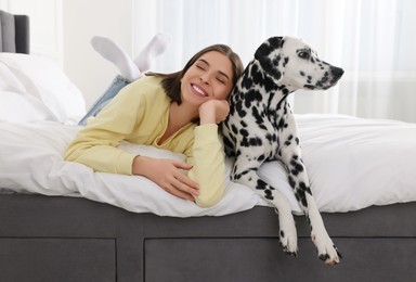 Beautiful woman with her adorable Dalmatian dog on bed at home. Lovely pet
