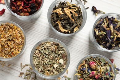 Flat lay composition with different dry teas on white wooden table